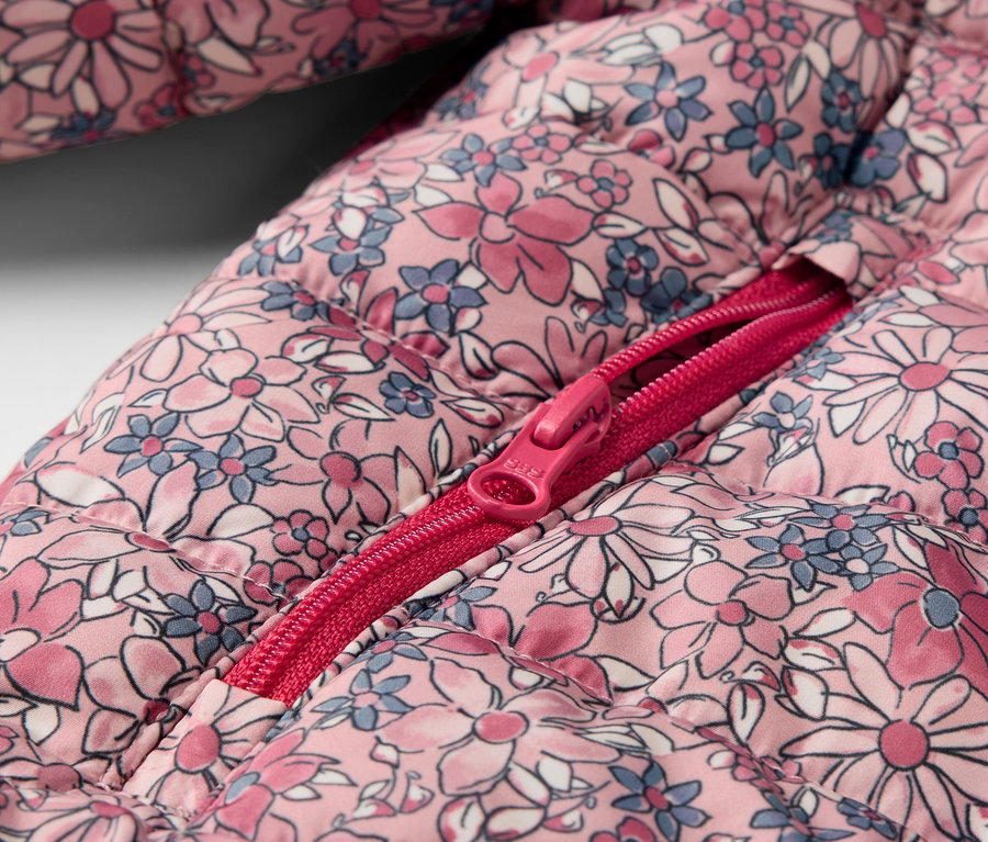 Gros plan sur un anorak matelassé pour enfants, à fleurs, avec une fermeture éclair ouverte.