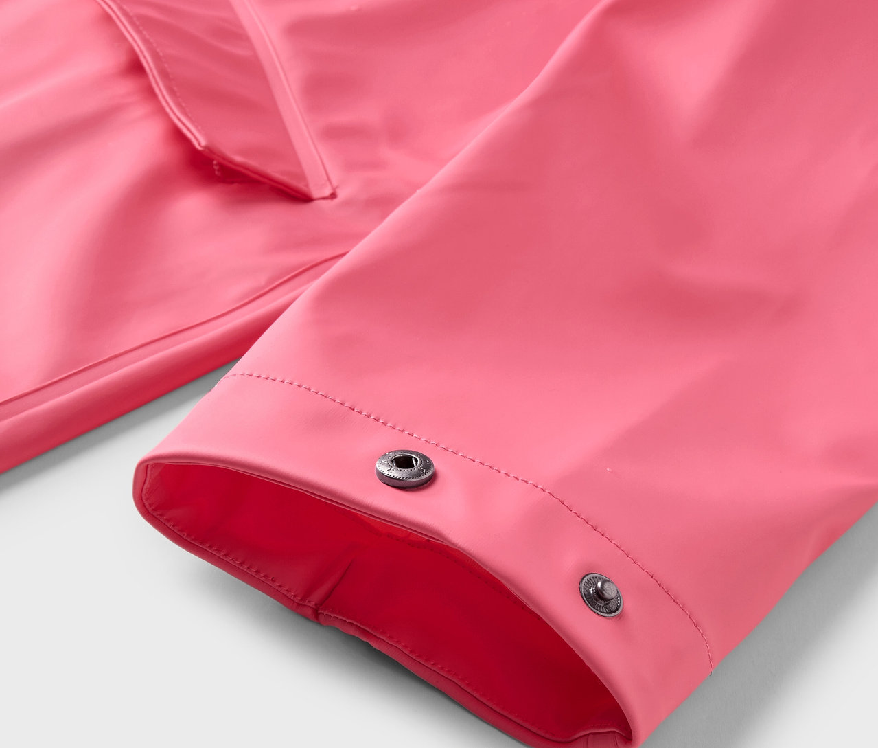 Gros plan sur un manteau de pluie rose avec des boutons-pression.