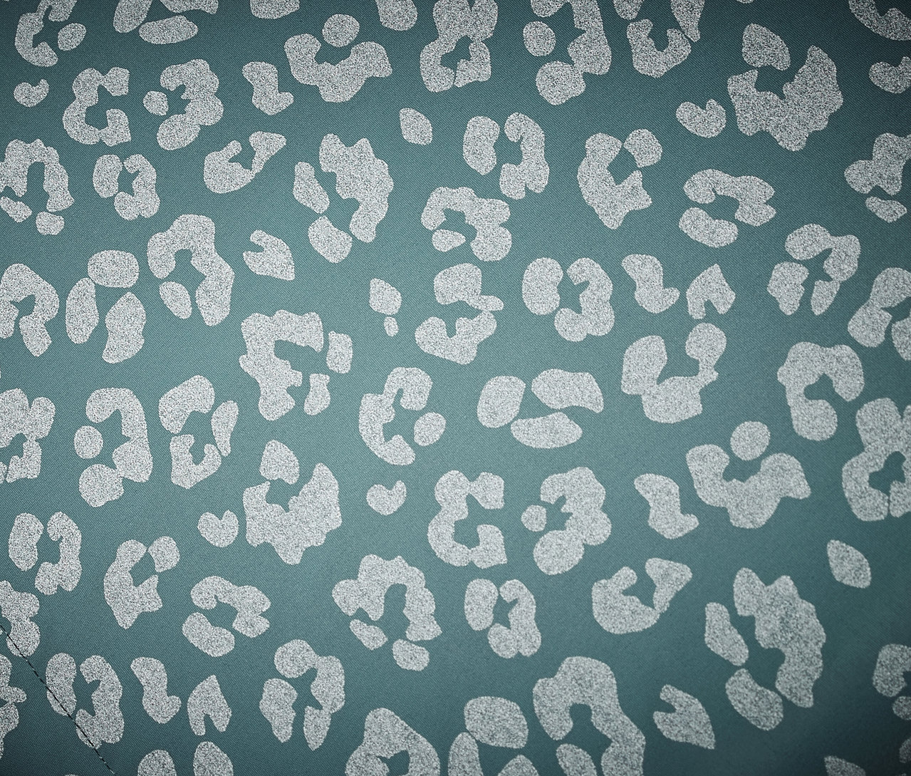 Gros plan sur une veste de pluie thermique pour enfant avec des éléments réfléchissants et un motif léopard.