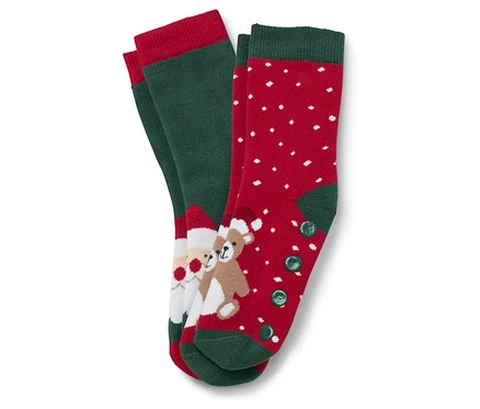 Deux paires de chaussettes de Noël. Une paire est verte avec une bordure rouge et une image du Père Noël et d'un ours en peluche. L'autre paire est rouge avec des points blancs et une bordure et des boutons verts.