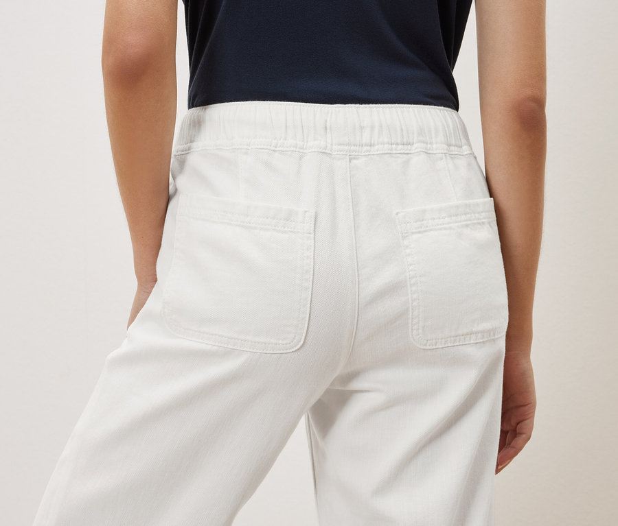 Vue arrière d'une femme portant un pantalon blanc.