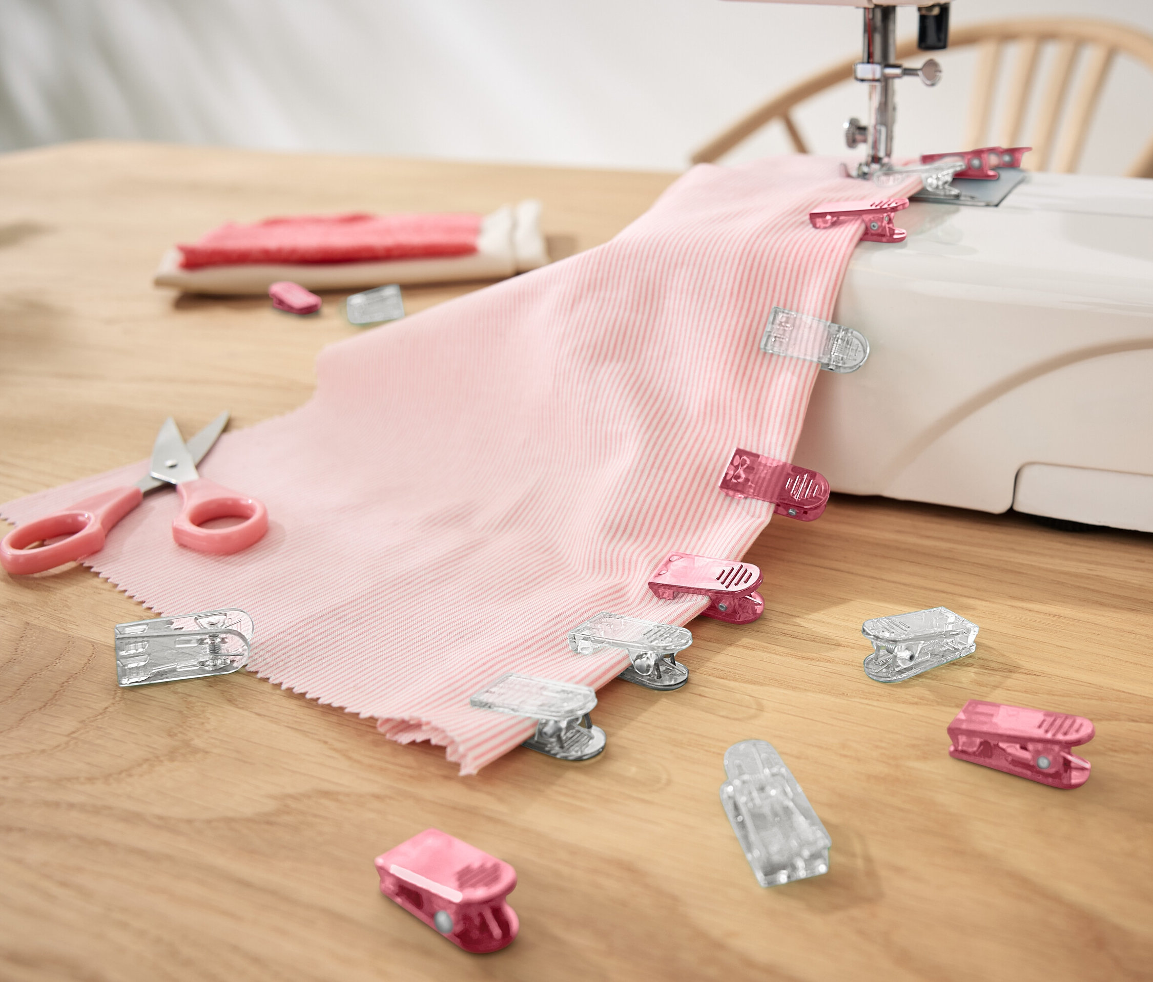 Tissu rose avec 20 pinces à tissu sur une machine à coudre.