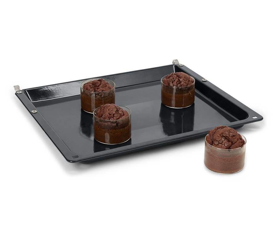 Quatre muffins au chocolat dans des verres sur une plaque de cuisson noire.