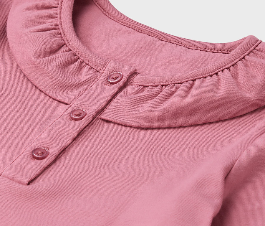 Gros plan d'une chemise rose avec col et boutons.