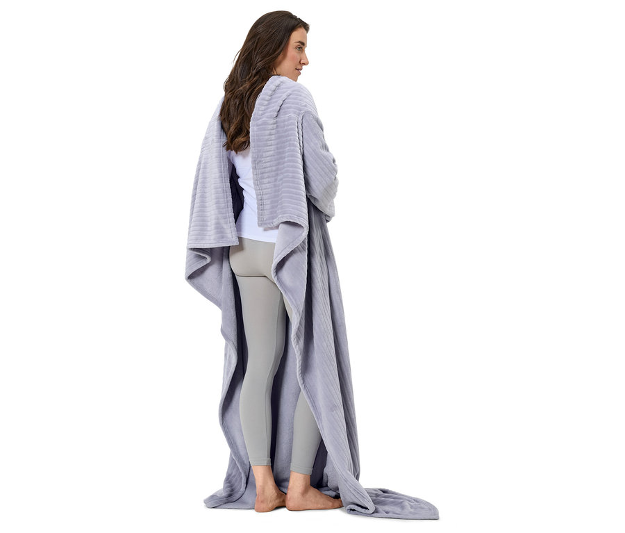 Une femme debout, dos à la caméra, enveloppée dans une couverture grise.