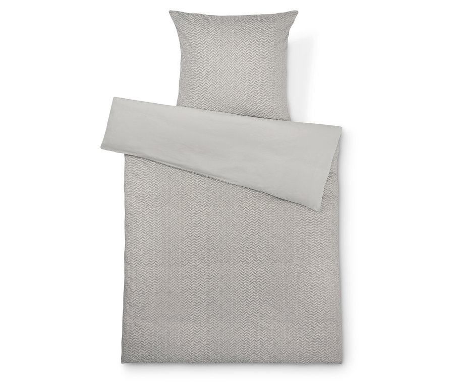 Linge de lit avec motif géométrique et jeté de lit gris clair.
