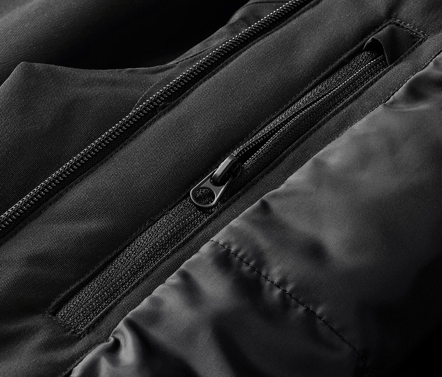 Gros plan sur une veste noire avec des fermetures éclair apparentes et des coutures matelassées.