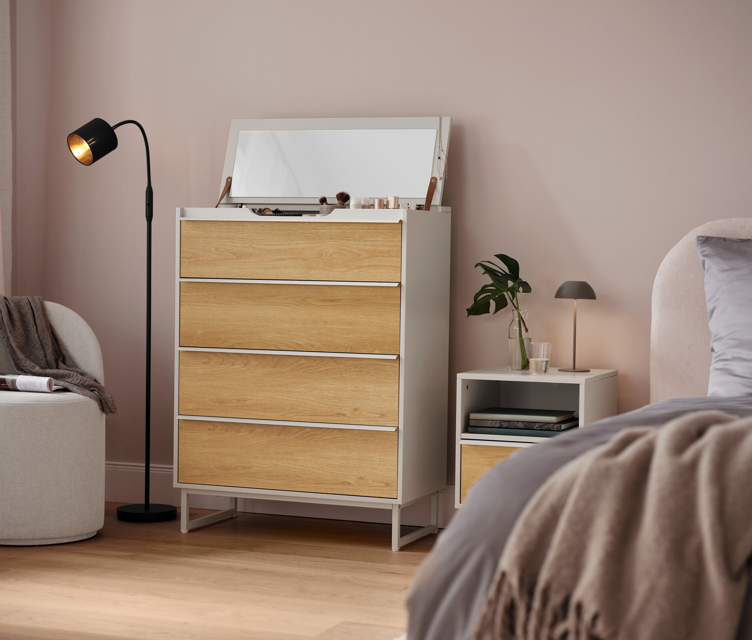 Chambre avec commode blanche à quatre tiroirs, miroir et lampe.