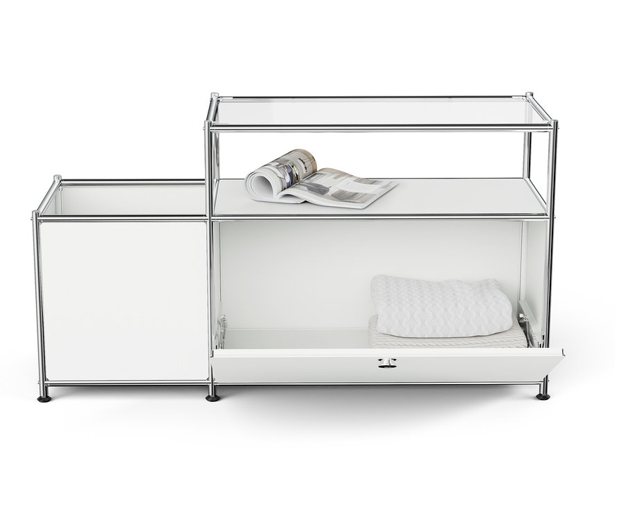 Système de rangement modulaire blanc avec étagères ouvertes et un tiroir, avec un magazine sur l'étagère supérieure et des textiles pliés dans le tiroir.