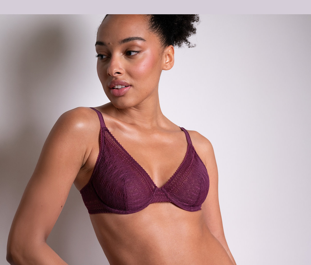 Femme portant un soutien-gorge à armatures en dentelle violette « Leila » de Passionata, regardant de côté.
