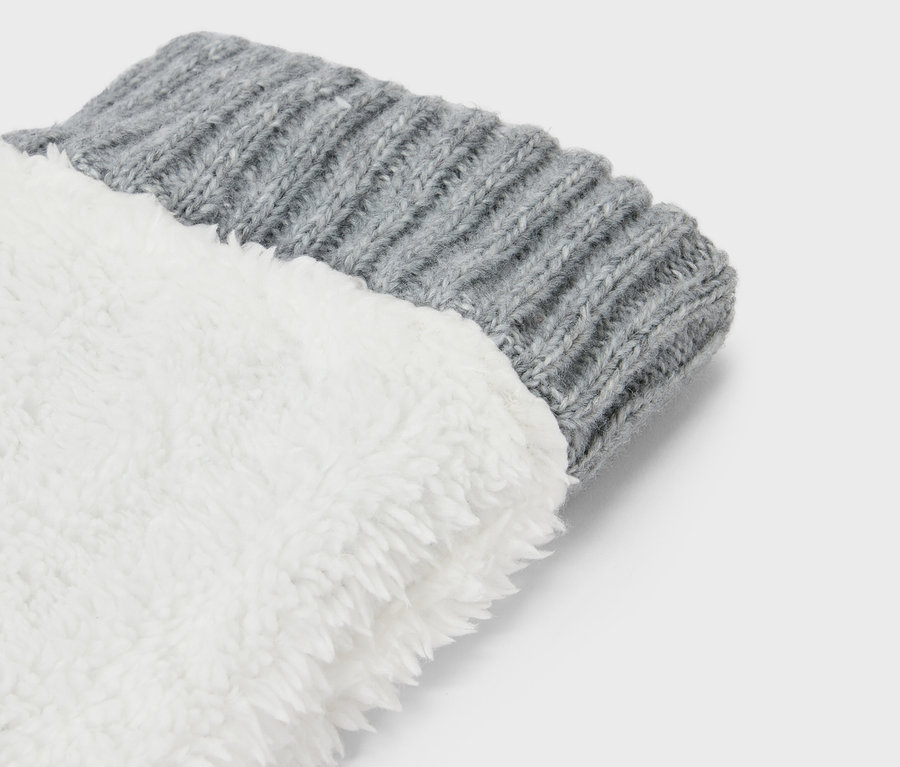 Gros plan du bord-côtes tricoté gris d'une chaussette avec une doublure blanche et duveteuse.