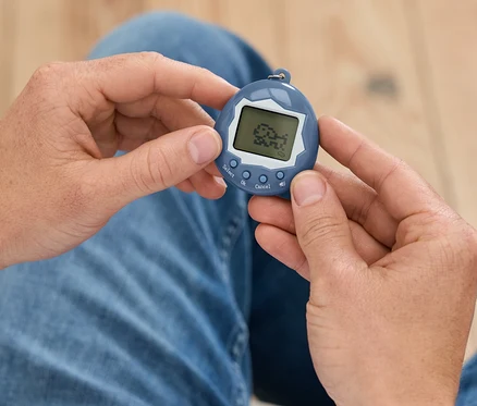 Un homme tient un Tamagotchi bleu dans ses mains.