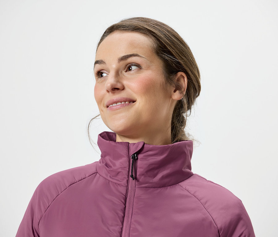 Femme aux cheveux bruns et veste rose regardant vers la droite.