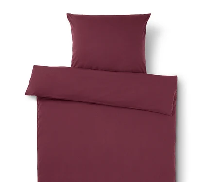 Linge de lit bordeaux avec oreiller sur le dessus.