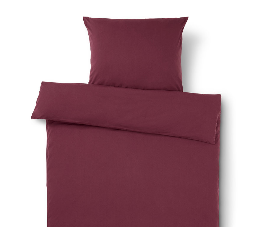 Linge de lit bordeaux avec oreiller sur le dessus.