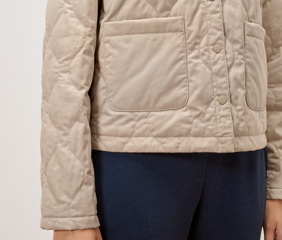 Veste matelassée beige avec boutons et poches.