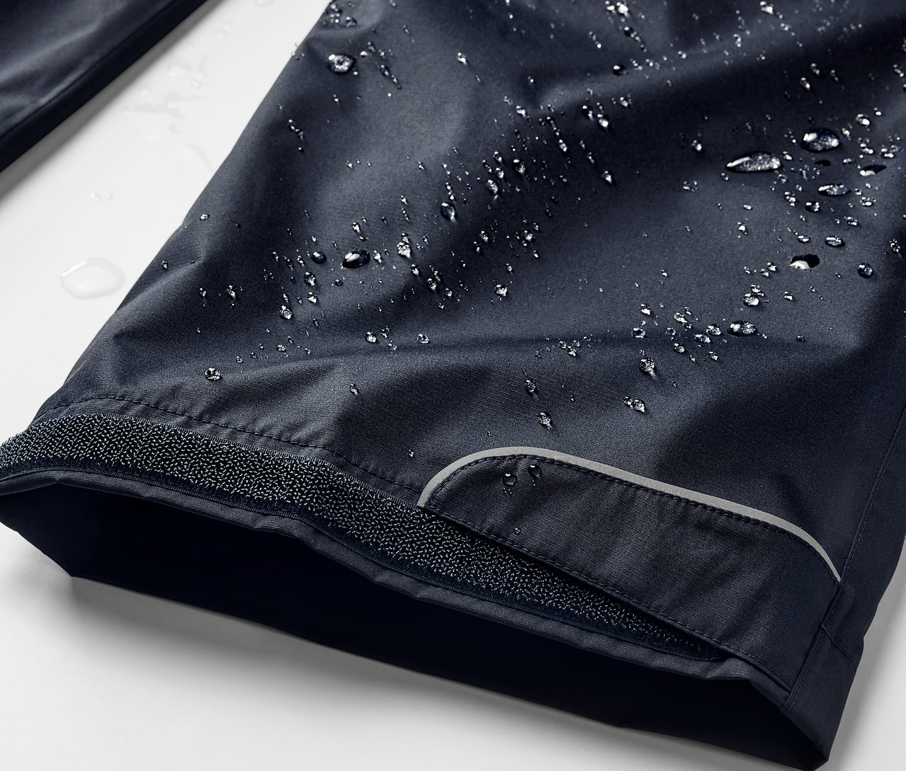 Gros plan sur un pantalon de pluie bleu marine avec des gouttes d'eau.