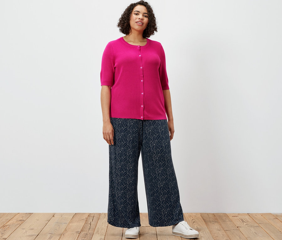 Une femme portant un cardigan en maille fine avec lin et un pantalon palazzo imprimé, bleu foncé et blanc crème.