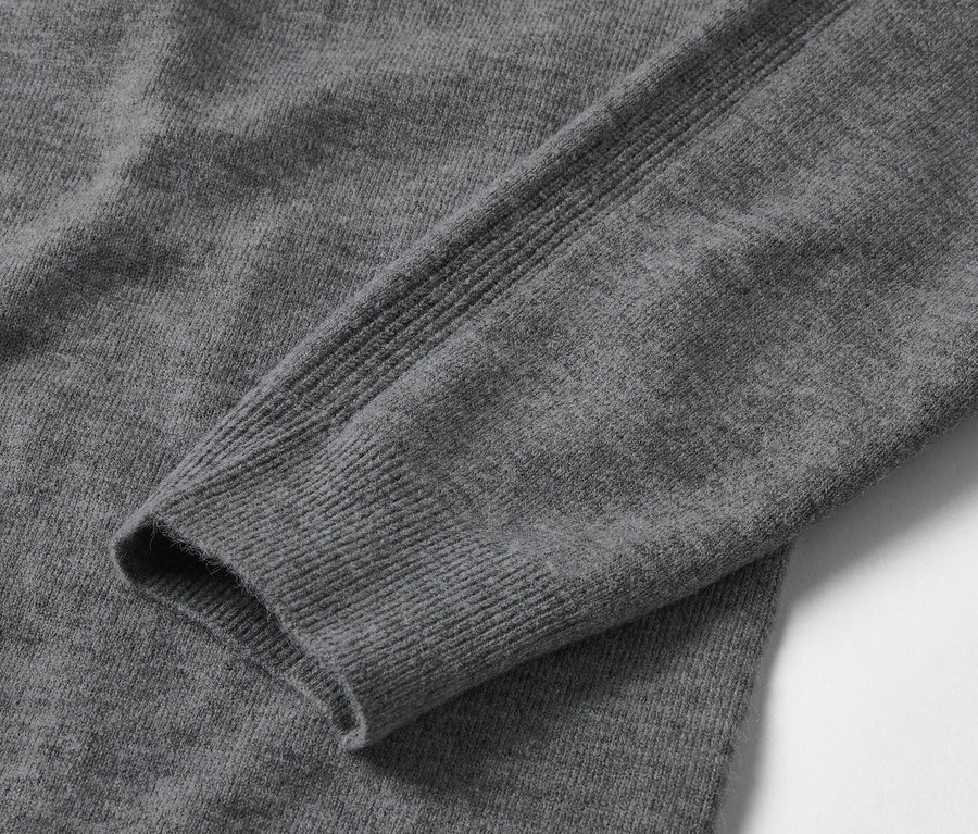 Gros plan sur un pull gris à manches longues.