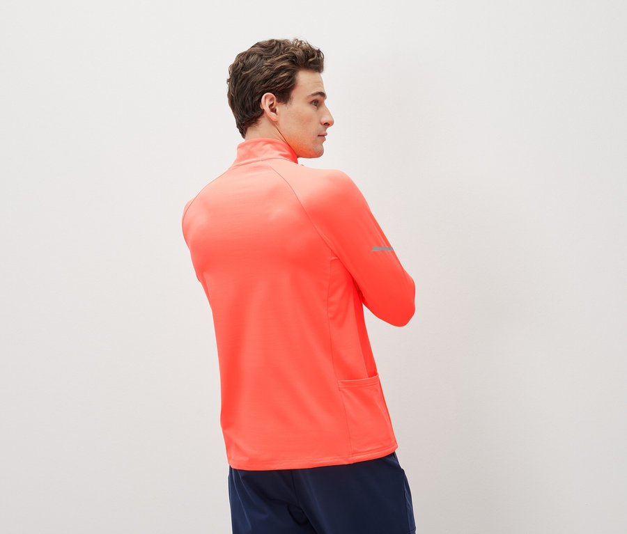 Homme portant un haut de sport corail à manches longues et un short de sport bleu marine.