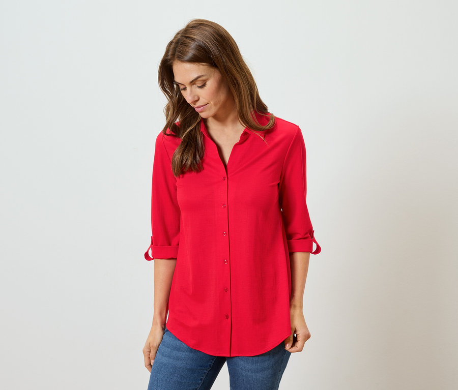 Femme portant une chemise rouge et un jean bleu.