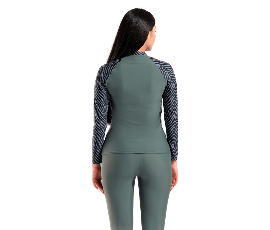 Vue arrière d'une femme aux longs cheveux foncés portant un haut de sport vert à manches longues avec des manches zébrées et un legging vert.