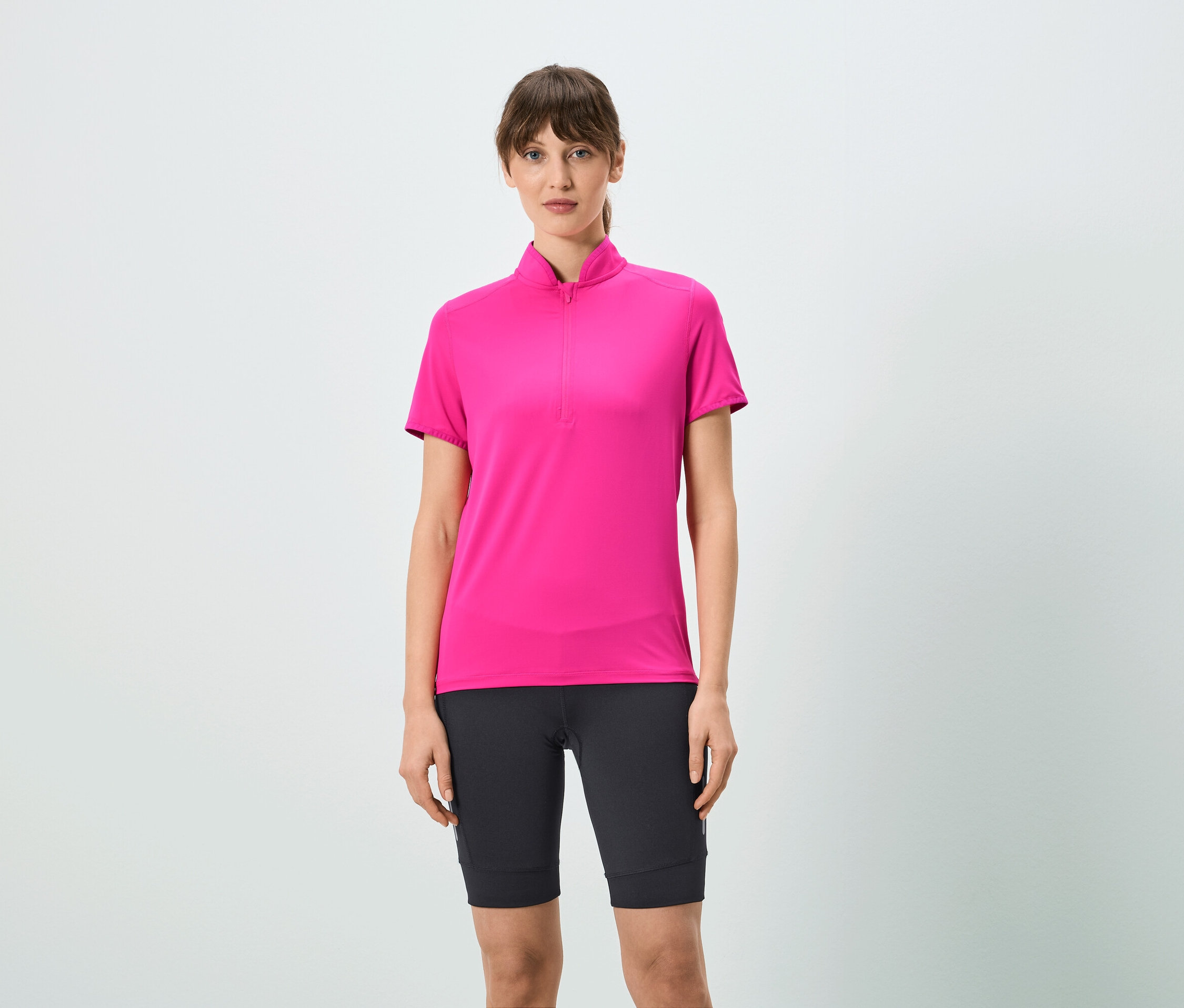 Une femme porte un t-shirt rose à fermeture éclair courte et un short noir.