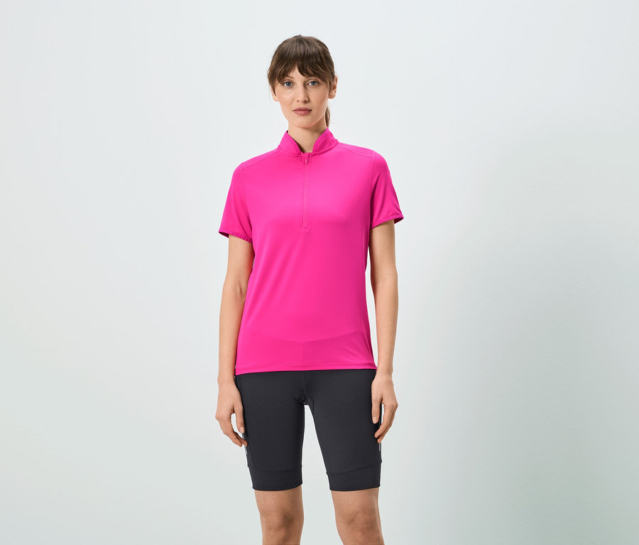 Une femme porte un t-shirt rose à fermeture éclair courte et un short noir.