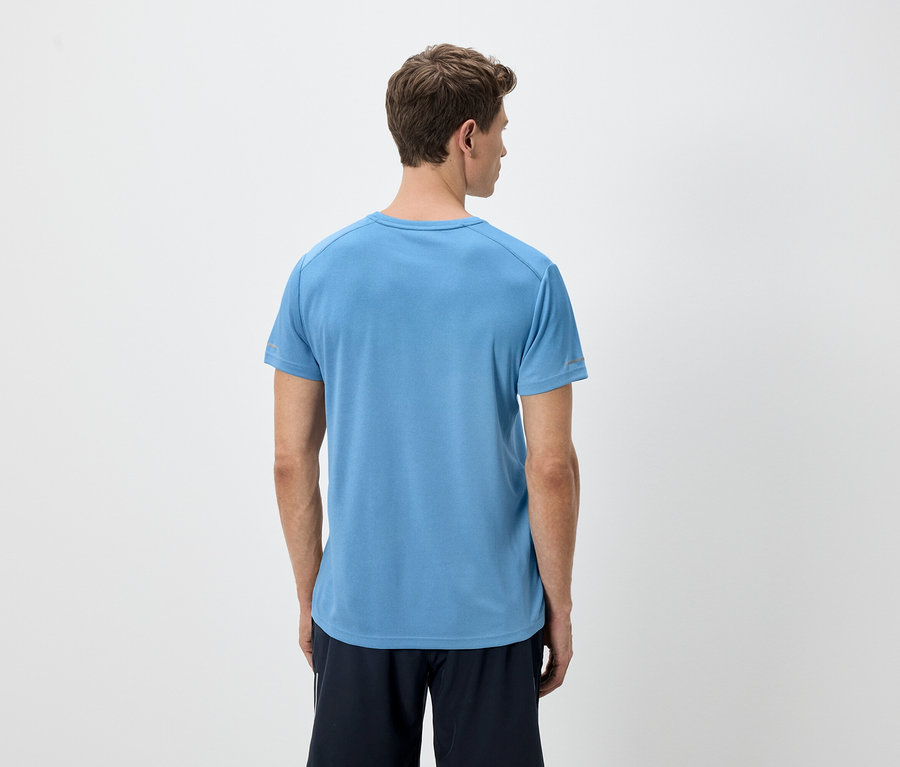 Vue arrière d'un homme aux cheveux châtain clair portant un t-shirt bleu et un short noir sur un fond blanc.