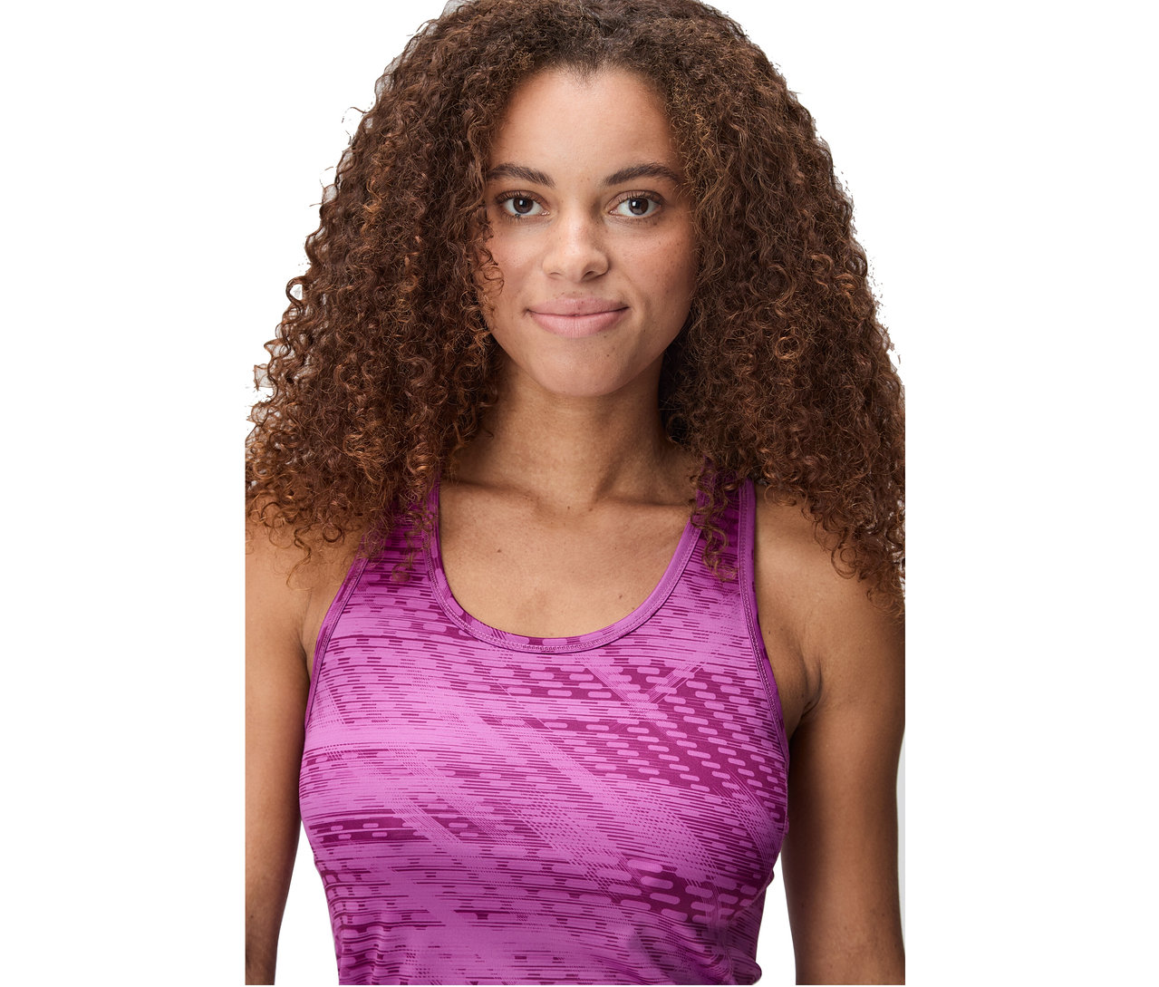 Portrait d'une femme aux cheveux bruns bouclés portant un débardeur rose à motifs.