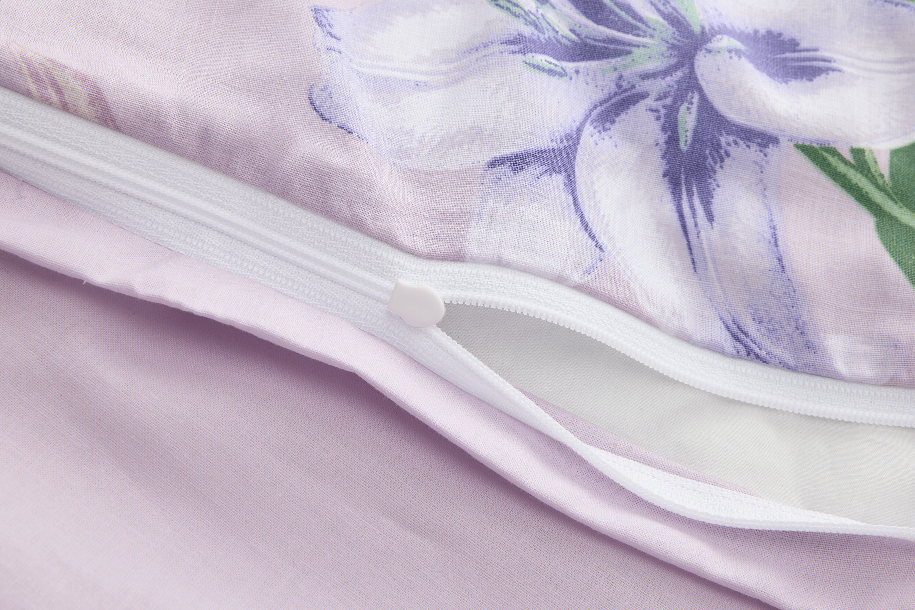 Gros plan d'une housse de couette violette partiellement ouverte avec un imprimé floral et une fermeture éclair.
