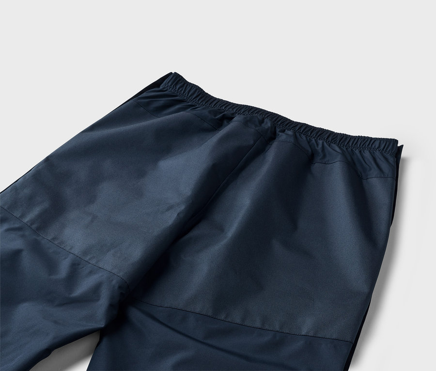 Gros plan sur l'arrière d'un pantalon bleu marine avec une taille élastique sur fond blanc.