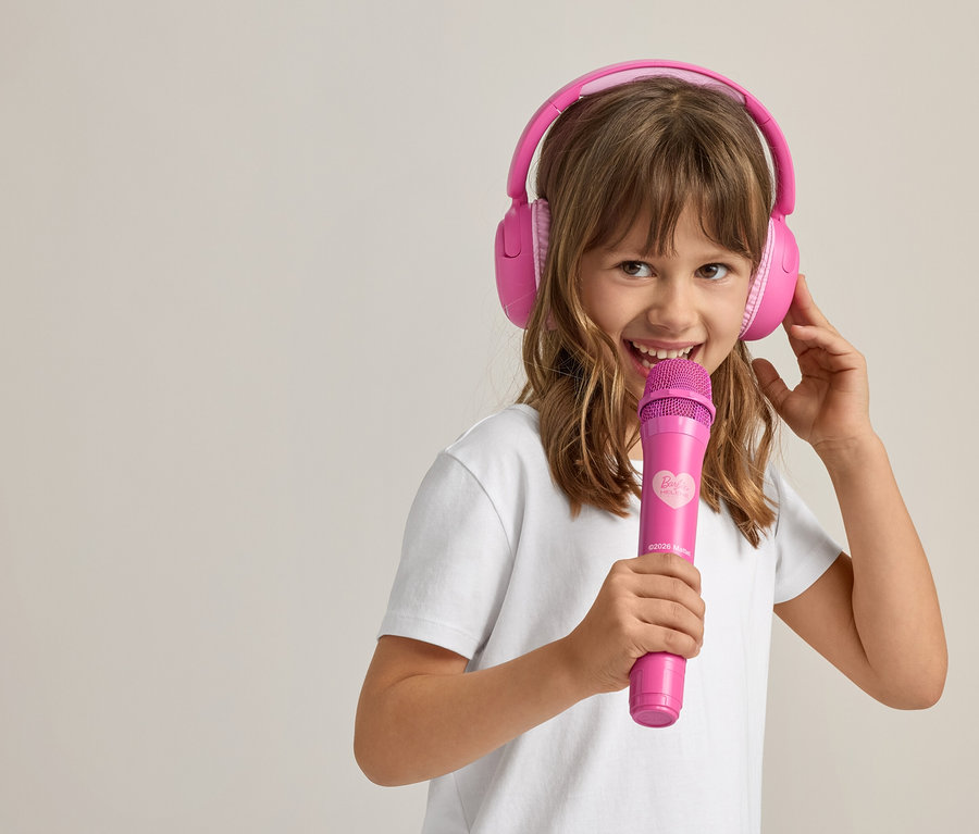 Fillette chantant avec un casque rose et un microphone.
