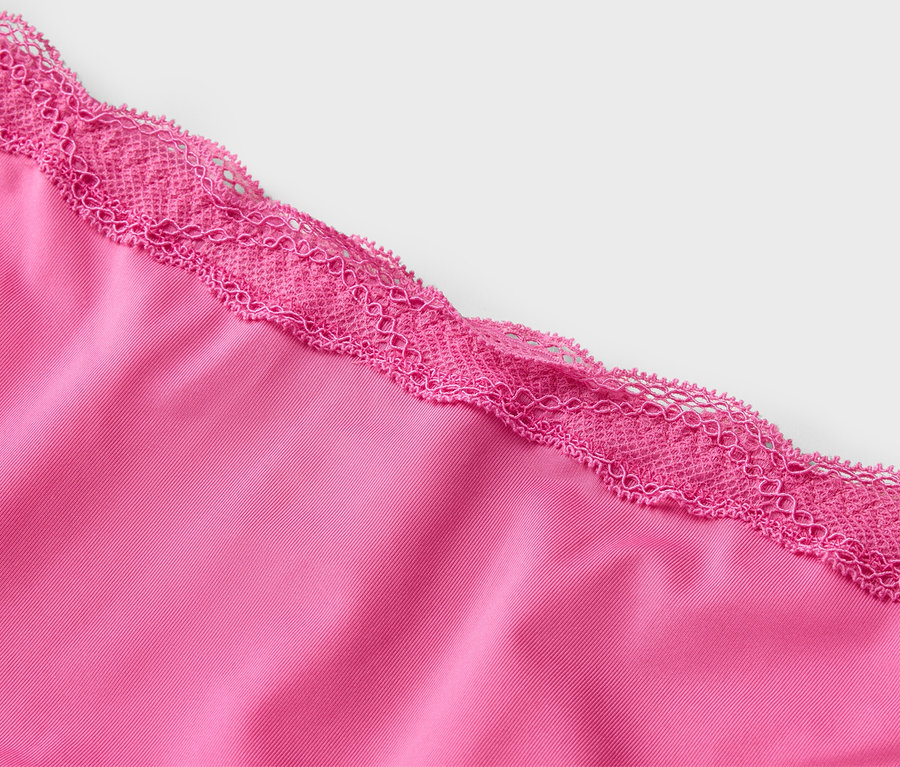 Gros plan d'un tissu rose avec de la dentelle rose sur le bord.