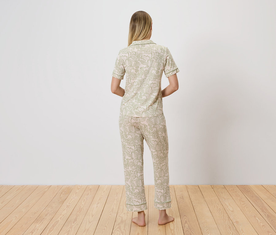 Vue de dos d'une femme blonde portant un pyjama clair à motifs floraux verts.