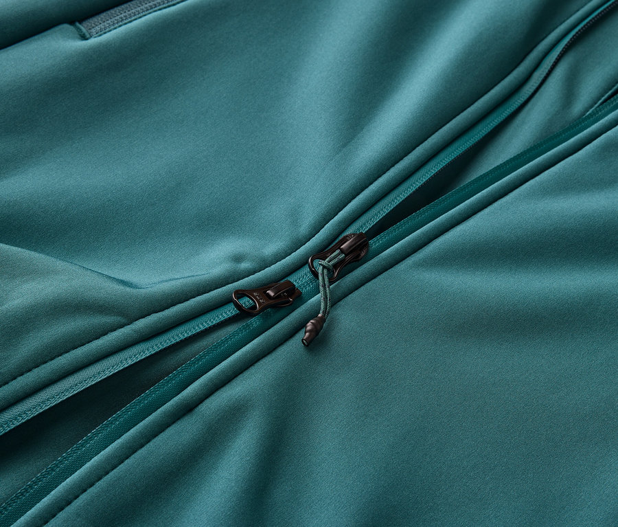 Gros plan d'une veste turquoise ouverte avec une fermeture éclair.