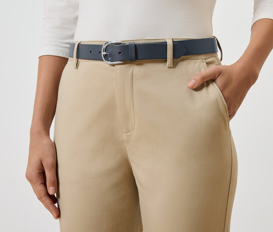 Une personne porte une ceinture bleu marine sur un pantalon beige.