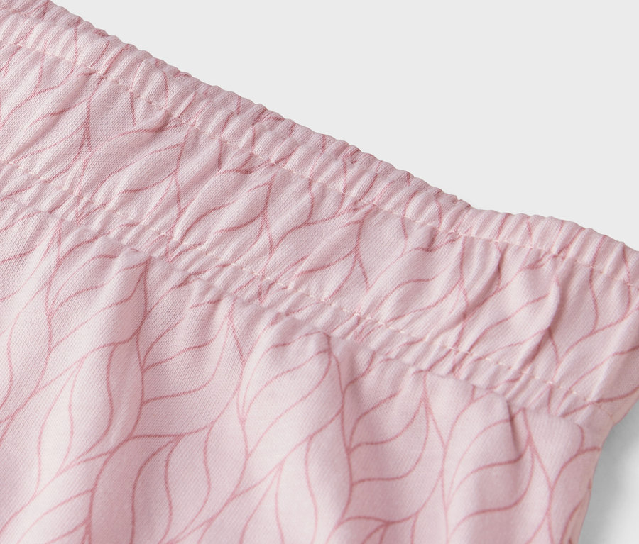Gros plan sur la ceinture d'un pantalon rose clair avec un motif de feuilles.