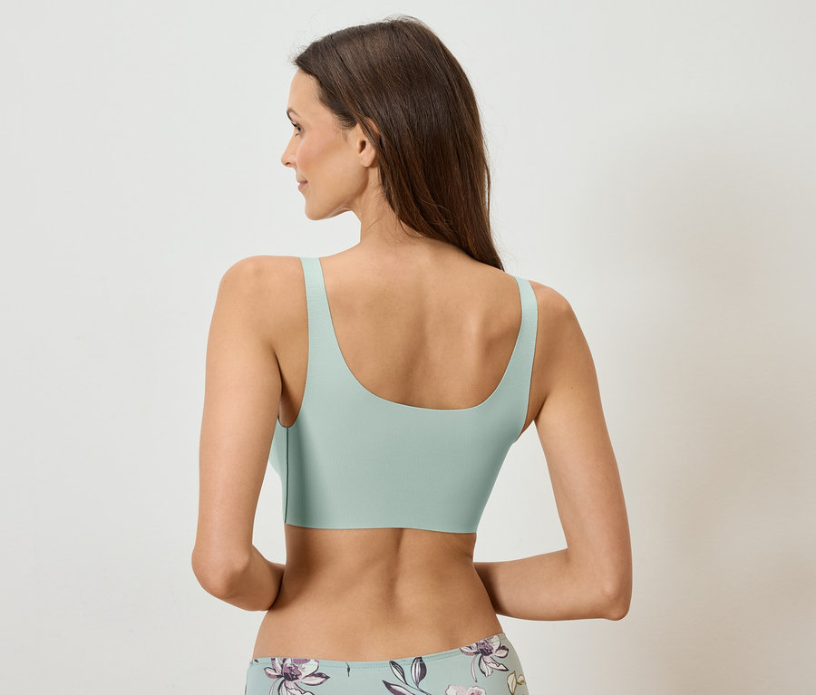Vue de dos d'une femme aux longs cheveux bruns portant un soutien-gorge vert menthe et des sous-vêtements à motifs floraux.