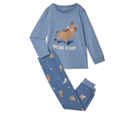 Pyjama bleu clair avec un haut à manches longues et un pantalon long. Le haut représente un chien marron sur un skateboard avec l'inscription "TOO COOL TO SLEEP". Le pantalon a un motif de chiens et d'os.