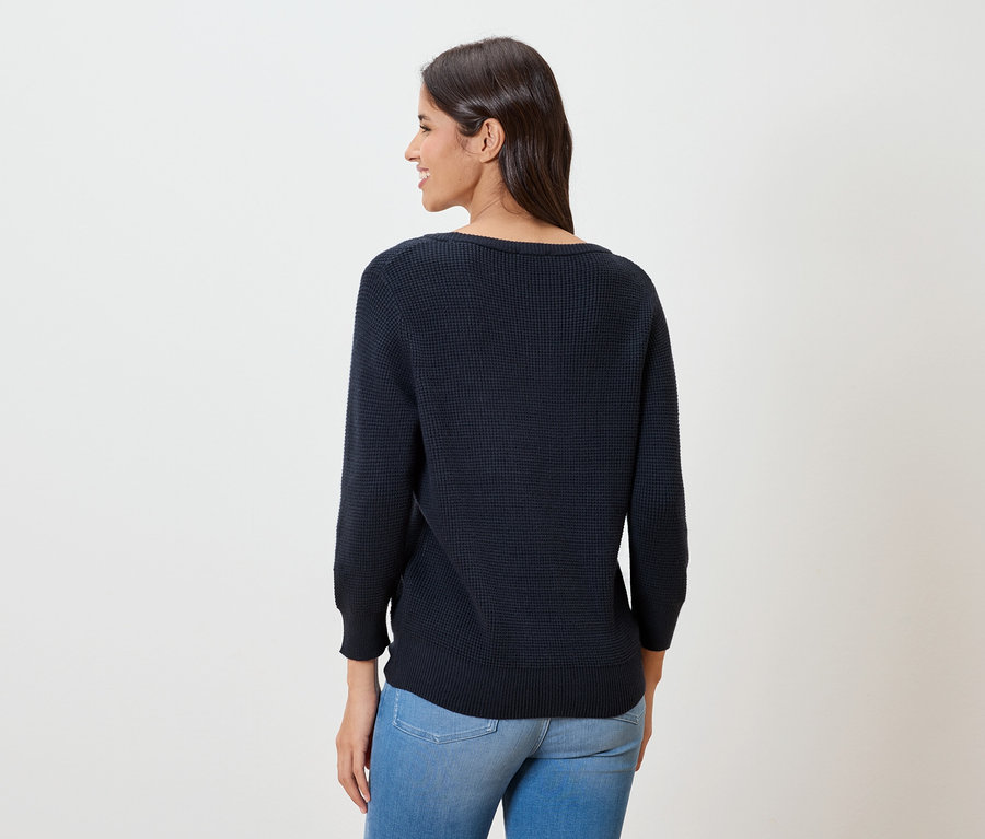 Femme vue de dos portant un pull fin bleu foncé et un jean.