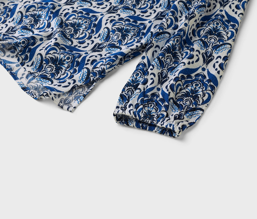 Gros plan sur la manche d'un chemisier à motifs bleus et blancs.