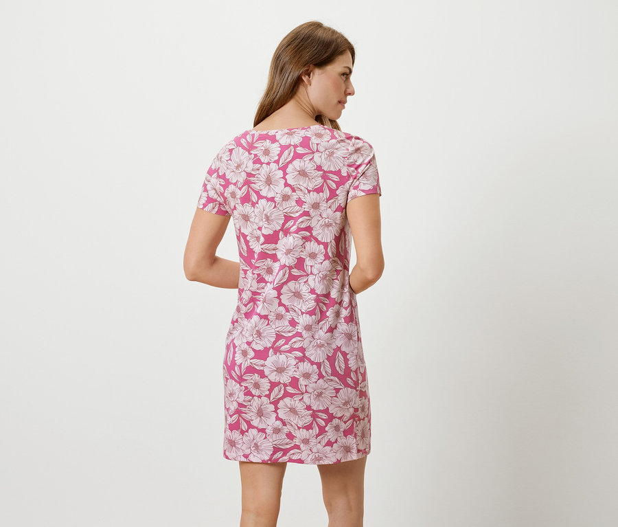 Une femme se tient dos à la caméra, portant une robe rose à imprimé floral.