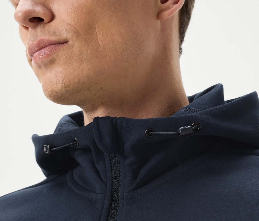 Gros plan d'un homme portant un sweat à capuche marine zippé.