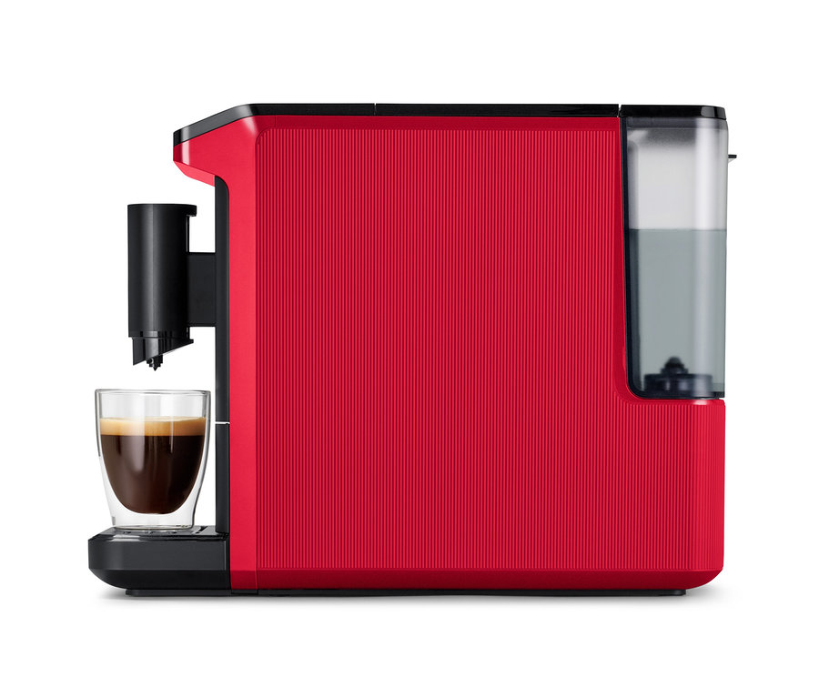 Machine à café entièrement automatique « Esperto mini », Lovely Red, rouge avec surface nervurée, bec verseur noir, une tasse de café en verre en dessous et réservoir d'eau à droite.