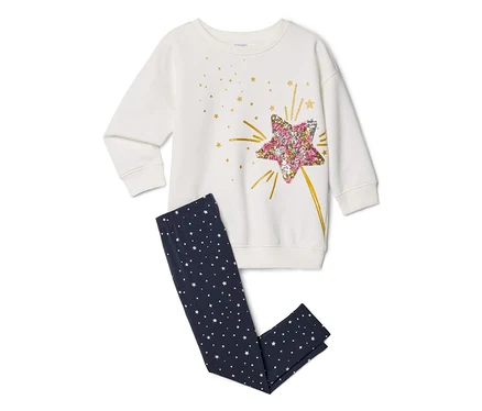 Haut blanc à manches longues avec un grand motif d'étoile à paillettes roses et dorées, associé à un legging bleu foncé orné de petites étoiles blanches.