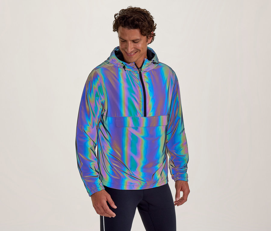 Homme souriant portant une veste à capuche irisée et réfléchissante avec un demi-zip et une poche avant, regardant vers le bas.