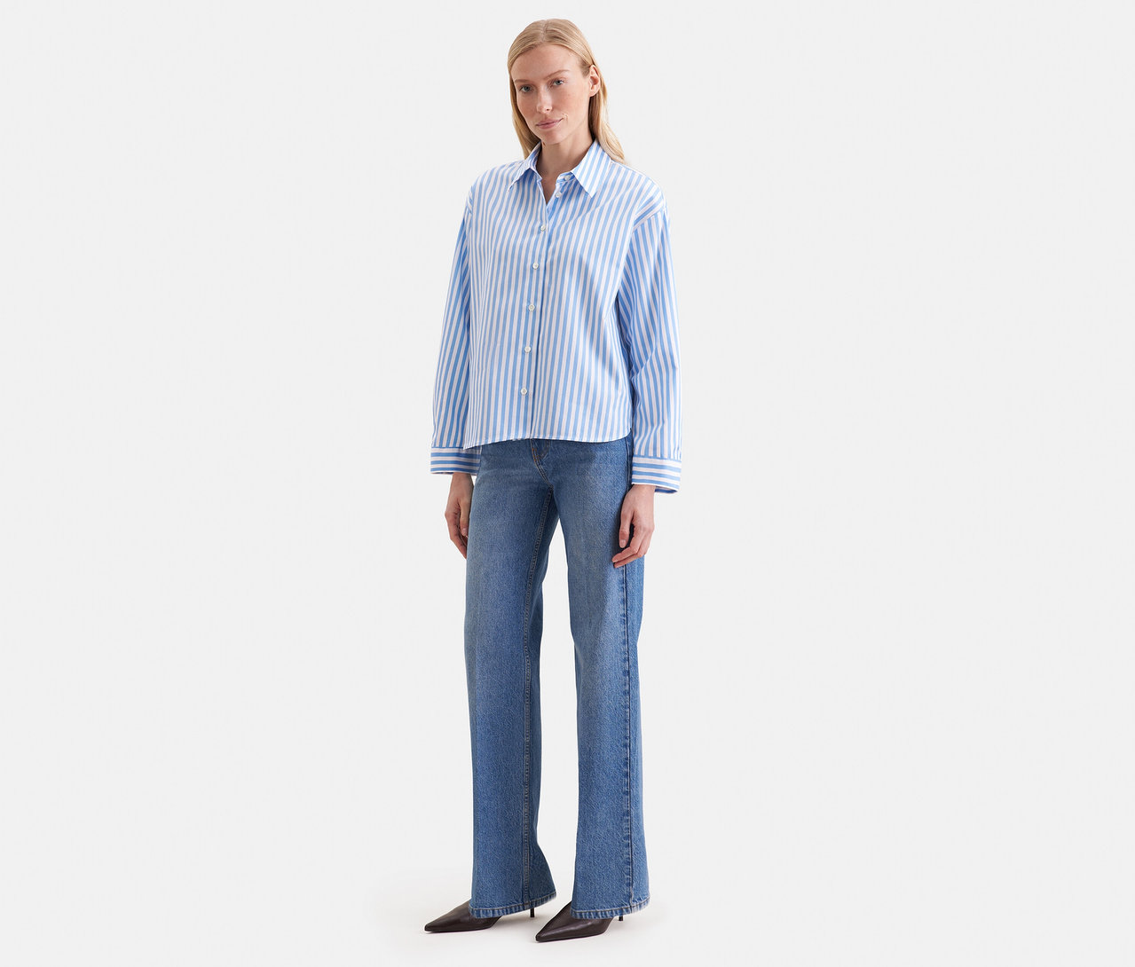 Une femme porte un chemisier oversize Seidensticker rayé bleu et blanc avec un jean bleu.
