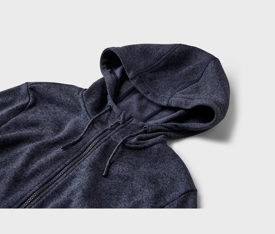 Sweat à capuche zippé bleu foncé avec cordons, posé sur une surface gris clair.