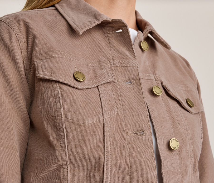 Gros plan d'une personne portant une veste en velours côtelé couleur mauve. La veste a un col, deux poches poitrine à rabat et des boutons dorés avec l'inscription 'MY STYLE'.